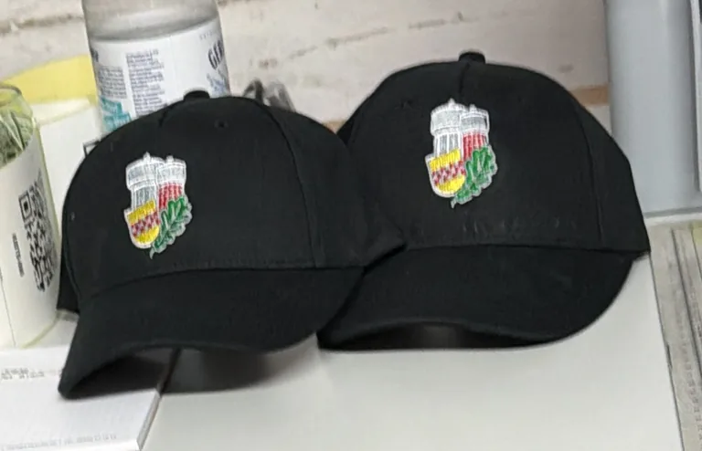 Zwei schwarze Caps mit gesticktem Wappen