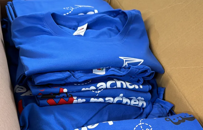 Karton mit fertig bedruckten blauen Shirts aus unserer Werkstatt