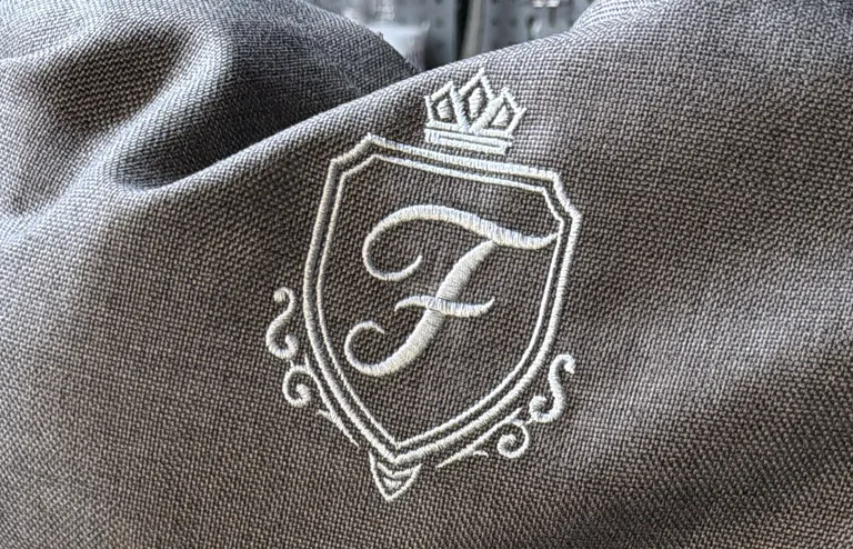 Gesticktes Wappen mit Krone auf grauem Stoff